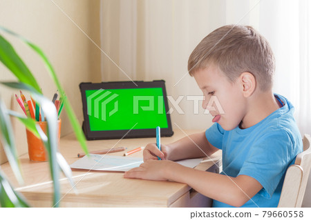 Cute boy writing at desk in his room, tablet with green screen stay on desk 79660558