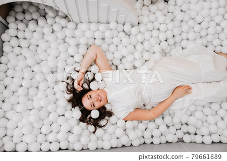 top view. an attractive woman in white clothes lies in a dry pool with balls top view. an attractive woman in white clothes lies in a dry pool with balls 79661889