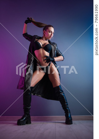 sexy woman in underwear, leather raincoat and long leather shoes in the studio on a neon background 79661990