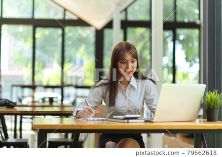 Portrait of female college student doing homework on laptop at cafe Portrait of female college student doing homework on laptop at cafe 79662618