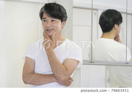 Middle-aged man standing in front of the mirror in the washroom 79663451
