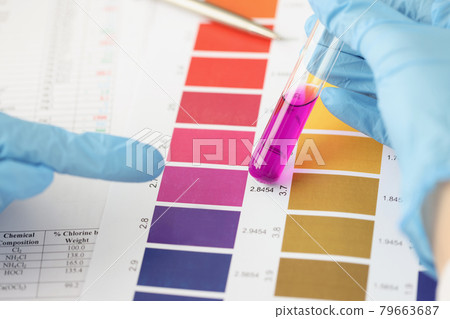 Scientist compares purple liquid in test tube to color bar Scientist compares purple liquid in test tube to color bar 79663687