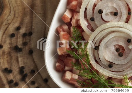 Italian pancetta, bacon cubes, diced ham, cutted pork, sliced onion, pepper in square white plate on wooden textured surface. Italian pancetta, bacon cubes, diced ham, cutted pork, sliced onion, pepper in square white plate on wooden textured surface. 79664699