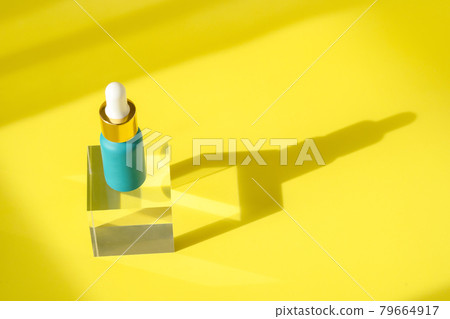 Hyaluronic acid skincare bottle on transparent crystall block podium pedestal. Cosmetics serum product with peptide and collagen. Modern packaging with shadows on yellow surface. Hyaluronic acid skincare bottle on transparent crystall block podium pedestal. Cosmetics serum product with peptide and collagen. Modern packaging with shadows on yellow surface. 79664917