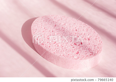 Bath sponge on pink shadow background. Oval spa shower scrub accessory. Skin care and concept Bath sponge on pink shadow background. Oval spa shower scrub accessory. Skin care and concept 79665140