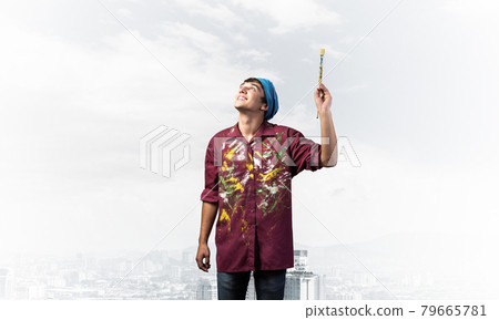 Smiling young painter artist holding paintbrush Smiling young painter artist holding paintbrush 79665781