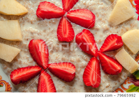 Milk oatmeal on a plate with fruits, strawberries and apples Milk oatmeal on a plate with fruits, strawberries and apples 79665992