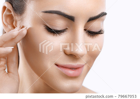 Facial Care. Female Applying Cream and Smiling.Portrait Of  Young Woman With Cosmetic Cream On Skin. Closeup Of Beautiful Girl With Beauty Product On Soft Skin, Natural Makeup Touching Face. 79667053