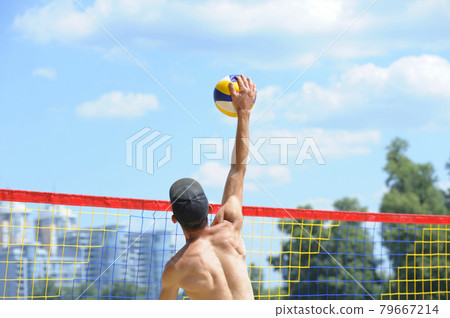 Beach volleyball. Male volley player hitting over the net ball attacking Beach volleyball. Male volley player hitting over the net ball attacking 79667214