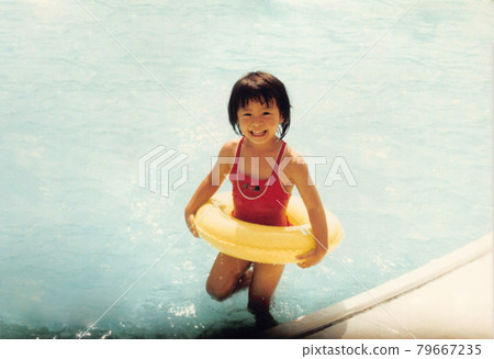 Old film photo Elementary school girl playing in the pool Old film photo Elementary school girl playing in the pool 79667235