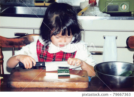 A girl who cuts a cucumber using an old film photo kitchen knife A girl who cuts a cucumber using an old film photo kitchen knife 79667363