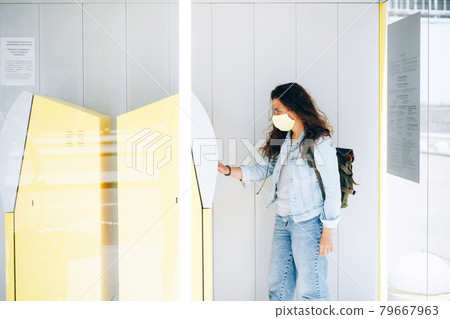 Young woman withdrawing money in face mask at ATM Young woman withdrawing money in face mask at ATM 79667963