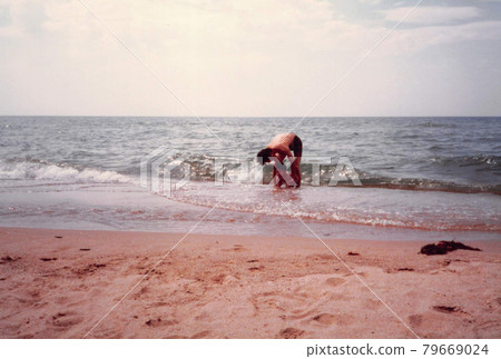 Old film photo: Father and little boy playing in the sea 79669024