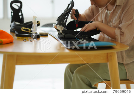 A woman grooming a snowboard board A woman grooming a snowboard board 79669046