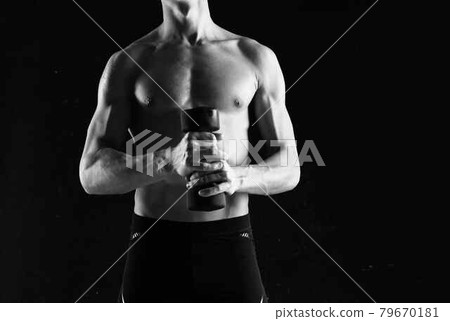 sporty man with dumbbells in hands pumping up muscles exercises dark background 79670181