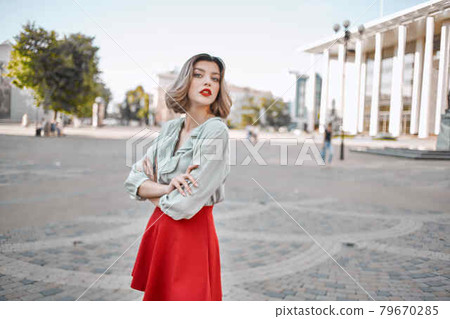 cheerful woman in a red skirt on the square in the city walk 79670285