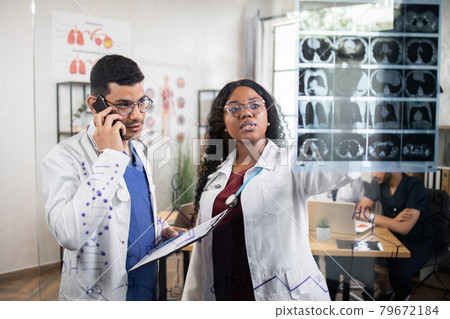 Diverse doctors analyzing CT scan picture during morning meeting Diverse doctors analyzing CT scan picture during morning meeting 79672184