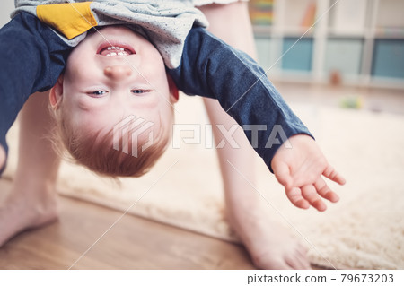 Mother holding upside down her laughing child. Mother holding upside down her laughing child. 79673203