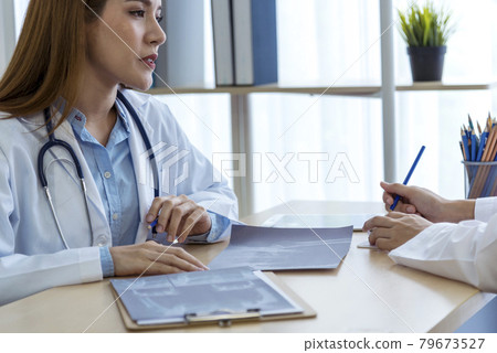 Two asian women doctors discuss meeting doctor's office medical clinic looking x-ray film consulting patient disease. Asian medical lab young women talking together discussing healthcare teamwork Two asian women doctors discuss meeting doctor's office medical clinic looking x-ray film consulting patient disease. Asian medical lab young women talking together discussing healthcare teamwork 79673527