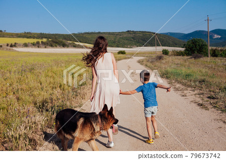 mother and son walk along the rural road to the field 79673742