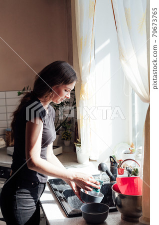 a woman housewife washes dishes in the kitchen 79673765
