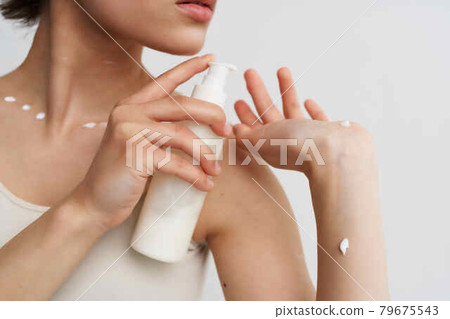 woman in white t-shirt applies cream to skin close-up woman in white t-shirt applies cream to skin close-up 79675543