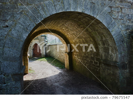 Dark arcade of roughly hewn stones with bright sunlight at the exit Dark arcade of roughly hewn stones with bright sunlight at the exit 79675547