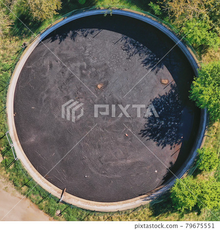 Vertical view down to a large circular tank for the storage of liquid manure Vertical view down to a large circular tank for the storage of liquid manure 79675551