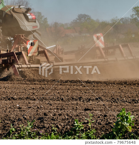 The farmer's plough churns up the dried earth of the field and causes a cloud of dust The farmer's plough churns up the dried earth of the field and causes a cloud of dust 79675648
