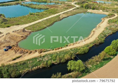 Aerial view of an active gravel pond beside the river Leine near Sarstedt, Germany, with a truck and piles of sand Aerial view of an active gravel pond beside the river Leine near Sarstedt, Germany, with a truck and piles of sand 79675792