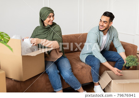 Happy man and woman in hijab packing or unpacking boxes Happy man and woman in hijab packing or unpacking boxes 79676941