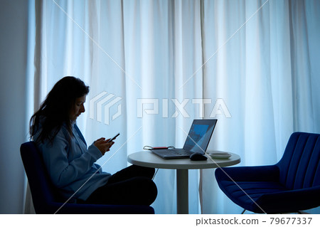 The girl is distracted by the phone at the workplace at the computer 79677337