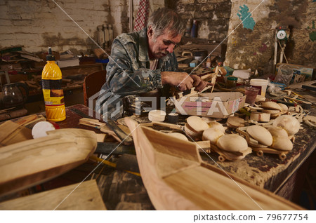Making wooden toys in workshop, craftsman in action, old artist at work 79677754