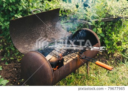 Making a fire in the grill for barbecue. Flame on the background of green grass in the evening in the back yard. Light a fire Making a fire in the grill for barbecue. Flame on the background of green grass in the evening in the back yard. Light a fire 79677985