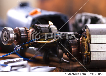 Power tool repair. Details of electrical appliance and repair tools on a wooden table in a repair shop Power tool repair. Details of electrical appliance and repair tools on a wooden table in a repair shop 79678053
