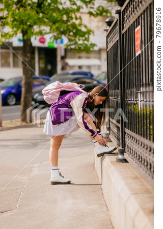 Young woman tying her shoelaces on her white boots 79678916