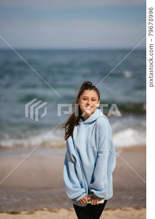 Beautiful woman in a public beach after walk with sporty look 79678996