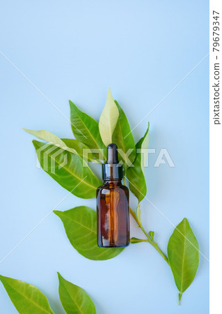 Flat lay ,top view of citrus essential oil or face serum in amber glass bottle with fruit branch leaves on blue background.Natural cosmetic 79679347