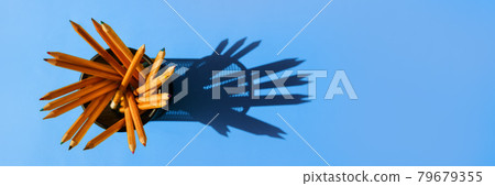 Graphite pencils in a metal grid-container on the office table top view on blue background. Graphite pencils in a metal grid-container on the office table top view on blue background. 79679355