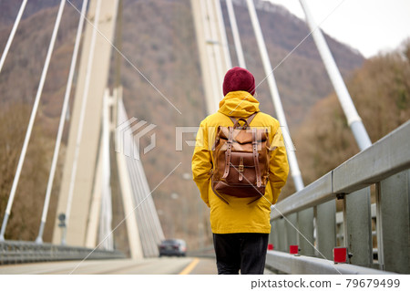 Rear view on man crosses bridge on the river, outdoor activity, travel concept Rear view on man crosses bridge on the river, outdoor activity, travel concept 79679499