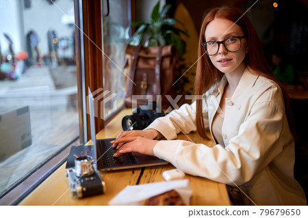 Confident woman traveler using laptop computer in cafe, working at coffee shop. 79679650