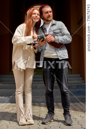 Happy caucasian couple taking pictures with retro film camera while walking. Happy caucasian couple taking pictures with retro film camera while walking. 79679743