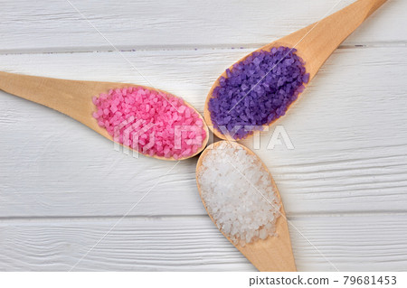 Three wooden spoons with colored salt of different color. 79681453