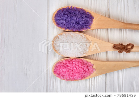 Spoons with colored bath salt on white wooden desk. Spoons with colored bath salt on white wooden desk. 79681459
