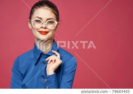Portrait of a woman in glasses and in a blue shirt red lips pink background model Portrait of a woman in glasses and in a blue shirt red lips pink background model 79683405