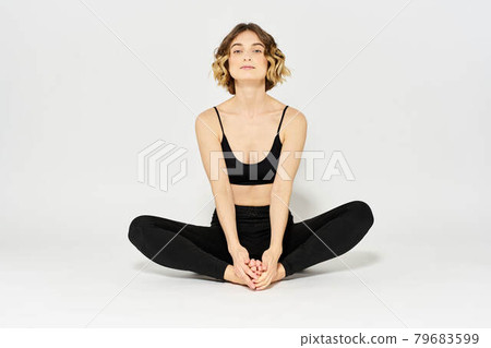Woman in leggings meditate in a light room with her legs crossed yoga asana 79683599
