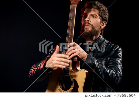 A man with a guitar in his hands leather jacket music performance rock star modern style dark background 79683604