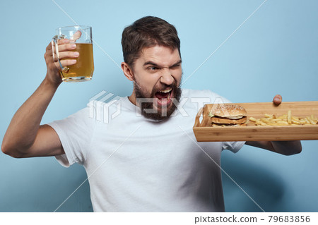 Cheerful man mug of beer fast food diet food lifestyle blue background alcohol 79683856