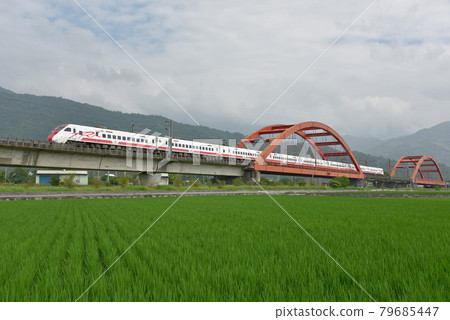 一座紅色的鐵橋，一列火車在行駛。 79685447