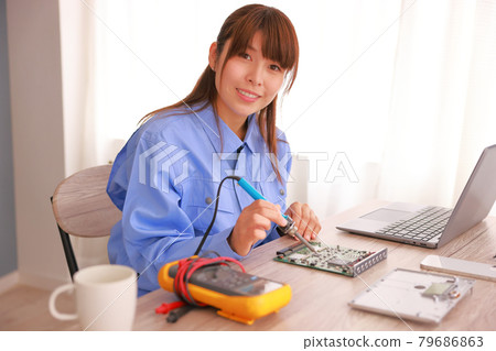 Work clothes_A woman looking up from working with a soldering iron 79686863